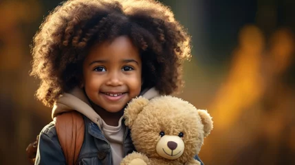 Poster Im Rahmen A cute little girl looks at the camera, smiles and play with toy bear © tashechka