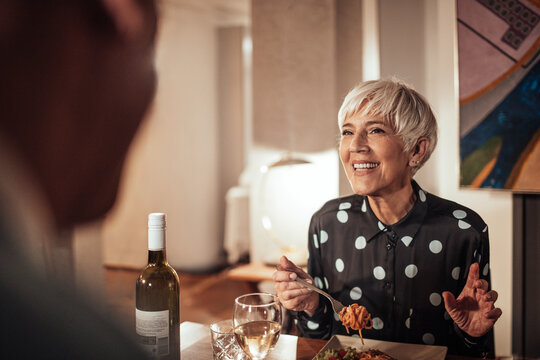 Senior woman having wine and dinner with her husband at home