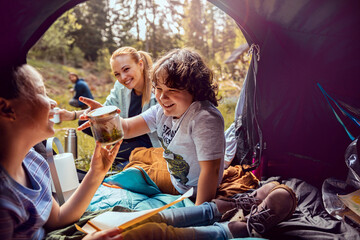 Young family collecting foliage in a jar while out camping in the woods