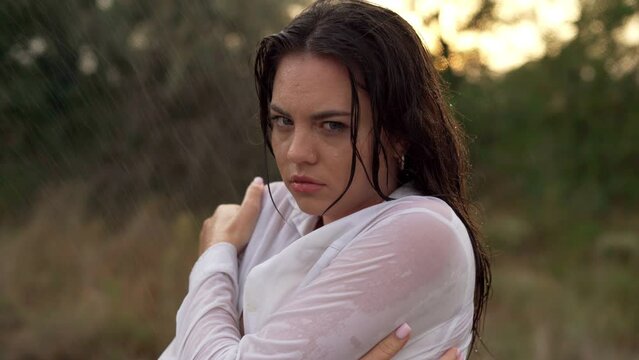 portrait of a young woman standing in clothes in the cold rain, all silent. There is an emotion of disappointment, anger and resentment on the face. Coward from the cold.