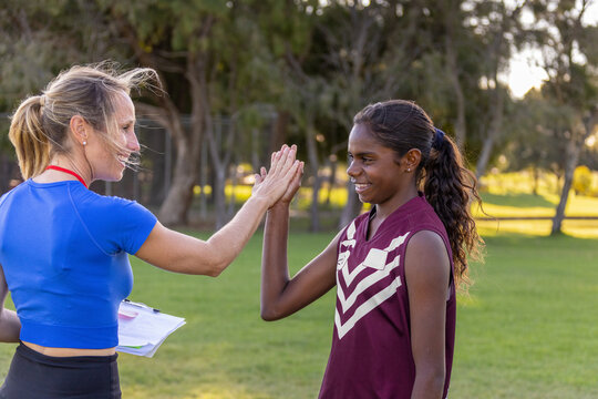 female coach high fives aboriginal student football player
