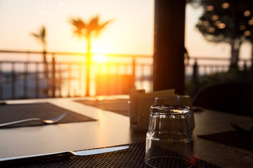 The rays of the sun at dawn fall on the table in a cafe with cutlery.