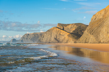 Cordoama Beach in Algarve Portugal, with sandy shore, dramatic cliffs and waves on Atlantic Ocean