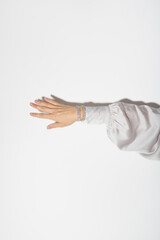 woman's hand in elegant silk clothes with shiny jewelry on a white background in hard light.