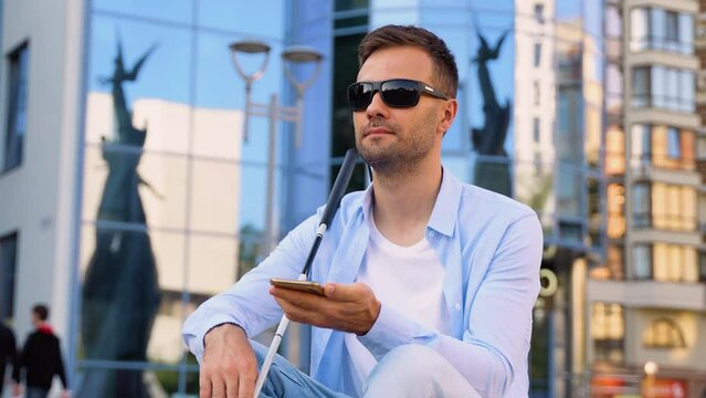 Young blind man speaks on the phone near business center