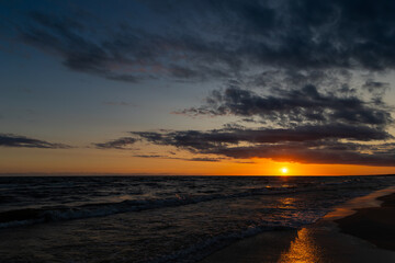 Orange sunset over the sea. Waves crashing onto the beach, dramatic sky. A static shot taken in the...