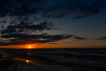 Orange sunset over the sea. Waves crashing onto the beach, dramatic sky. A static shot taken in the...