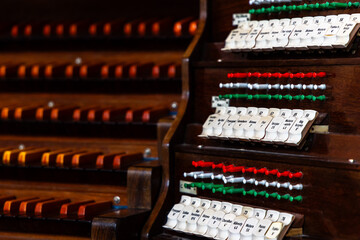 Wooden keyboard of an antique church pipe organ. The photo was taken in the semi-darkness of the...