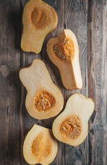 Ripe pumpkins on a wooden background.Whole and cut fruits of a yellow gourd.Top view.Seasonal vegetable autumn recipes