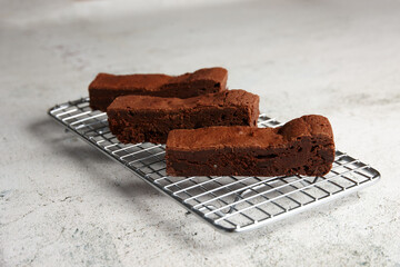 Three pieces of chocolate brownie on a baking rack