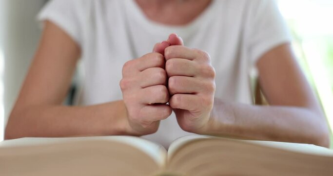 Woman prays with hands clasped on Bible faith and hope. Crisis of christian life and prayer to God