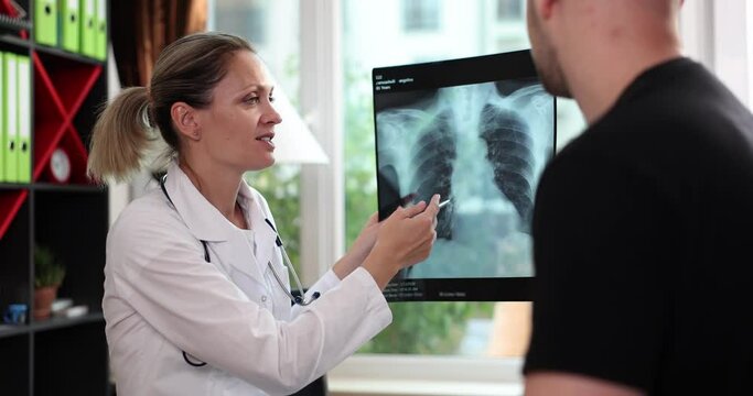 Doctor points to damaged area on x-ray of lungs to man patient. Medicine and routine examination