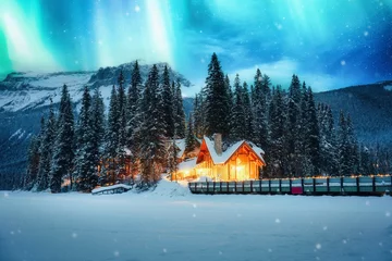 Fototapeten View of Northern lights glowing over Emerald Lake Lodge with snowy forest on winter at Yoho national park, Canada © Mumemories