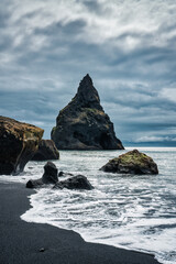 Moody Reynisdragar natural rock formation on Reynisfjara black sand beach in Atlantic ocean at Iceland