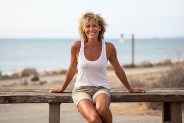 smiling attractive older woman in white t-shirt sitting against the background of the sea