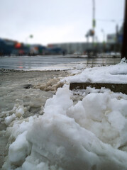 Pile of dirty melted snow on road. Winter is here. Frosty Cold weather. Snowfall in city. Problem of street snow removal. Messy. Chilly. Cityscape. Snowdrifts with pollutants and salt. Climate change.