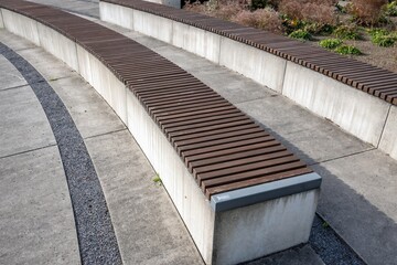 modern curved bench in concrete with wooden support in park