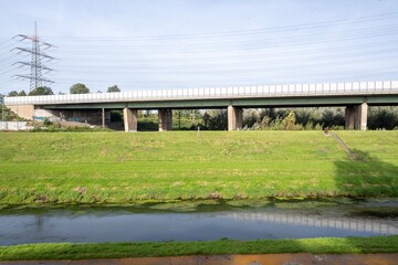 long motorway bridge with meadow and small canal in front