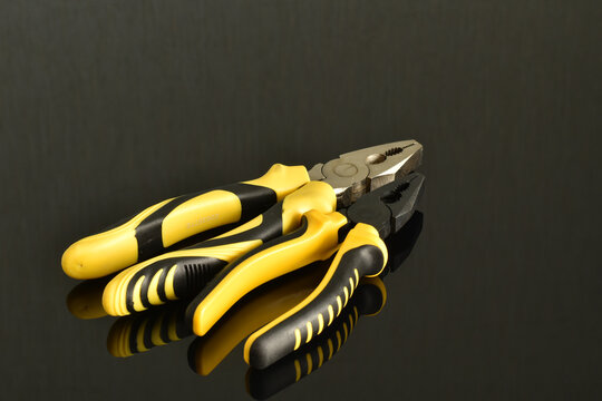 Mechanic's tools: ordinary pliers with yellow handles.