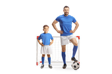 Fototapeta na wymiar Man and a boy with a soccer ball wearing blue sport jerseys and standing in front of a mini goal