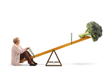 Full length profile shot of an elderly woman and a broccoli on a seesaw