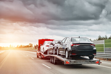 Transporting cars on the flatbed truck. Tow truck with a cars on the highway road. Vehicle...