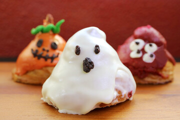 Three of Halloween Ghosts Shaped Sugar Glazed Croissants on Wooden Background