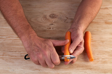 Men's hands are peels fresh carrots with a vegetable cutter