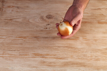 Men's hands are peels fresh onion with knife