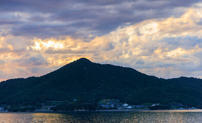 Dramatic sunset clouds over small coastal village and mountain