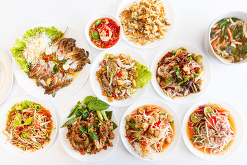 Top view: Somtum - Spicy Papaya Salad, Grilled pork neck, Larb moo - Spicy Minced Pork Salad and Crispy Fried Mushroom.Salad with Grilled Pork Neck.Blue Crab Salad. Three Mushroom Curry.  