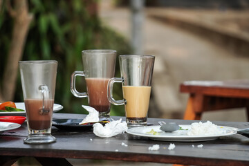 Empty dish white plate and drinking glass with traces and pieces of food. Unfinished or finished lunch, dinner, breakfast bowl on table. Dirty, empty, not clean. Finished White plate Spoon and Fork.
