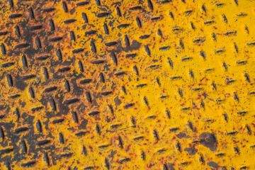 Old rusty yellow diamond metal plate background, grunge texture of bright metallic sheet with repetitive diagonal oval shape pattern, embossed steel surface protect slipping for stair or ramp floor
