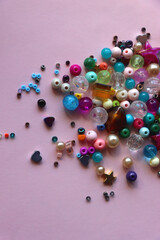 Various colorful beads on bright pink background. Top view.
