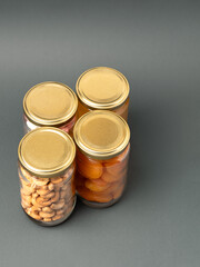 Group of jars with cashew nuts, dried apricots, honey and other food on   plain background