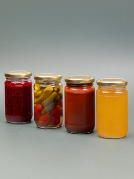 Group of jars with honey , marinated tomatos and gherkins  tomato sauce and raspberry jam on plain background. Various ingredient.