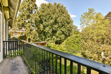 a balcony with trees in the back and bushes on the other side of the house, as seen from outside
