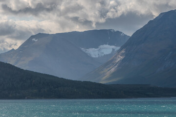 Unmelted snow on mountainside. Beautiful fjord view in Norway. Turquoise water on a sea.