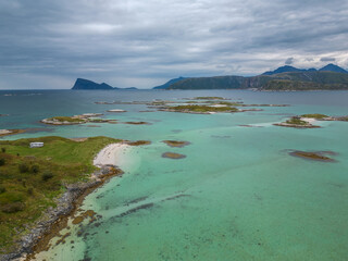 Obraz premium High angle view of archipelago on turqouise ocean. Rocky mountains on a background. Coast of Sommaroy in Norway.