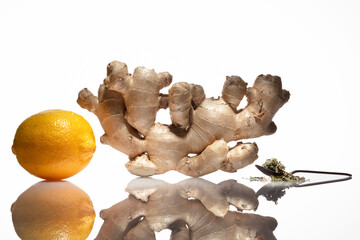 Ginger tea. Ginger root with lemon, herbal in tea spoon on a white table and background.  Healthy...