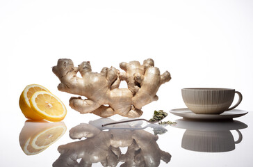 Ginger root with slices lemon, herbal in tea spoon, cup on a white table and background. Ginger...