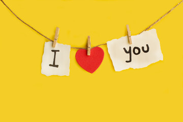 Un cartel colgado con la palabra I love you sobre un fondo amarillo liso y aislado. Vista de frente y de cerca. Copy space - obrazy, fototapety, plakaty