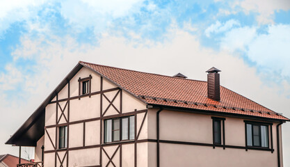 The upper part of the roof of a very neat and colorful house. The roof of the house from a metal profile against the sky