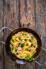 Mediterranean orzo salad with tuna, lemon and capers on wooden background