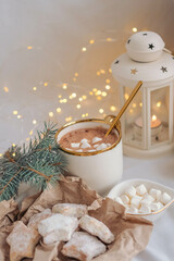 Hot chocolate with marshmallows and cookies on the background of a Christmas garland