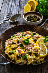 Mediterranean orzo salad with tuna, lemon and capers on wooden background