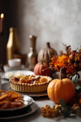 Naklejka premium Traditional American pumpkin pie on festive table decorated for Thanksgiving Day. Autumn plants and pumpkins as decoration