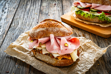 Sandwich with mortadella pistachios, tapenade and cheese on wooden table

