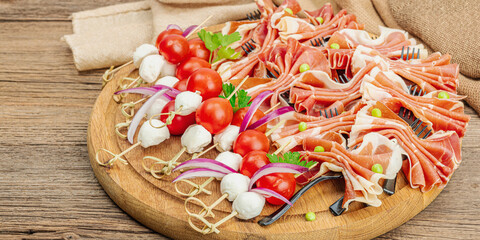 Set of picnic snacks on skewers. Jamon, mozzarella, cherry tomatoes, peas, fresh greens