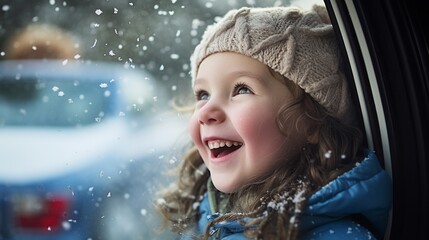 Happy little girl watching and playing with snow from an open car window on the trip of a snowy winter holiday, joyful kid have fun with snow flakes.